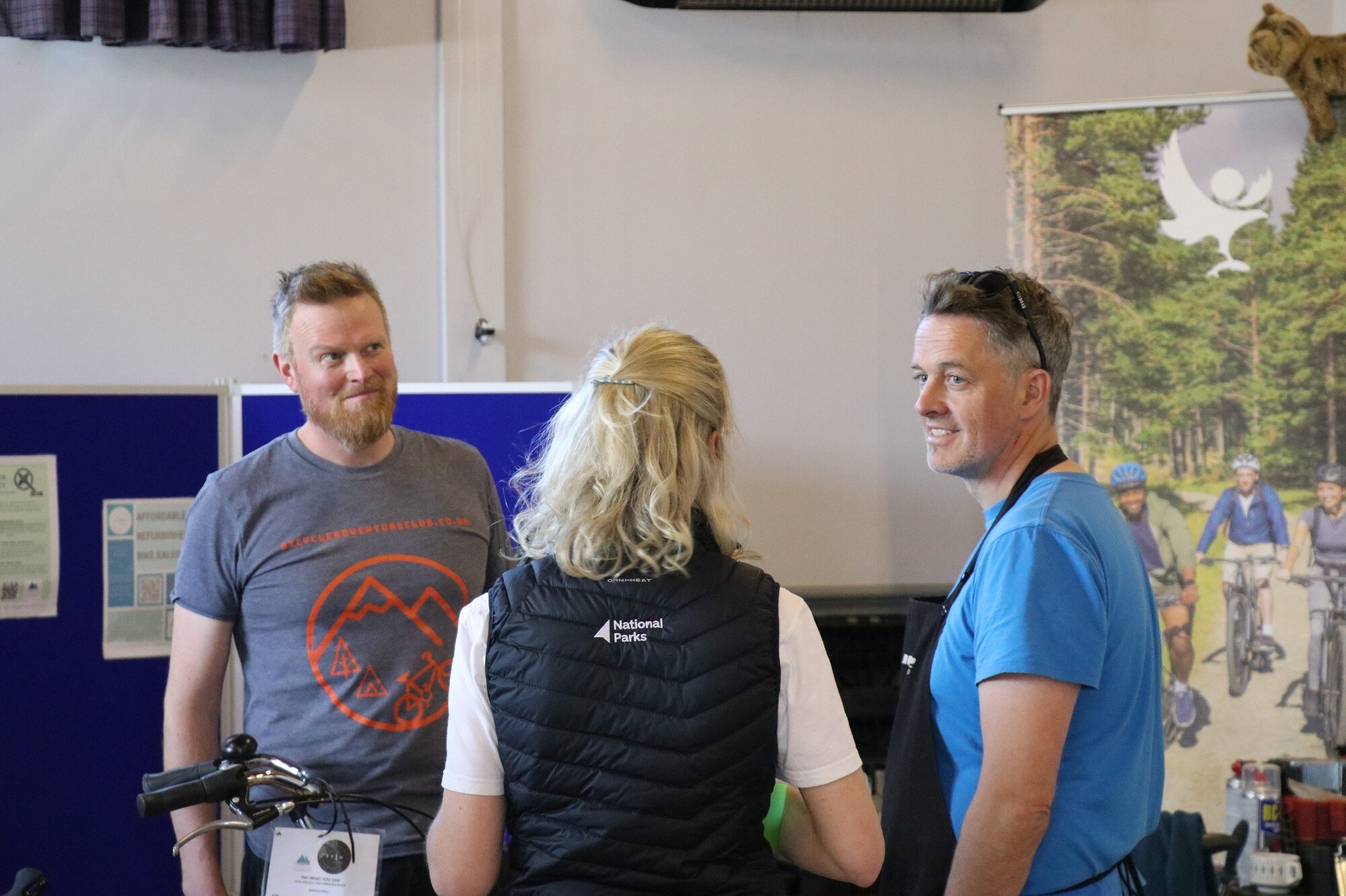 Three people having a conversation in front of information boards at a C2030 drop-in event in Carrbridge