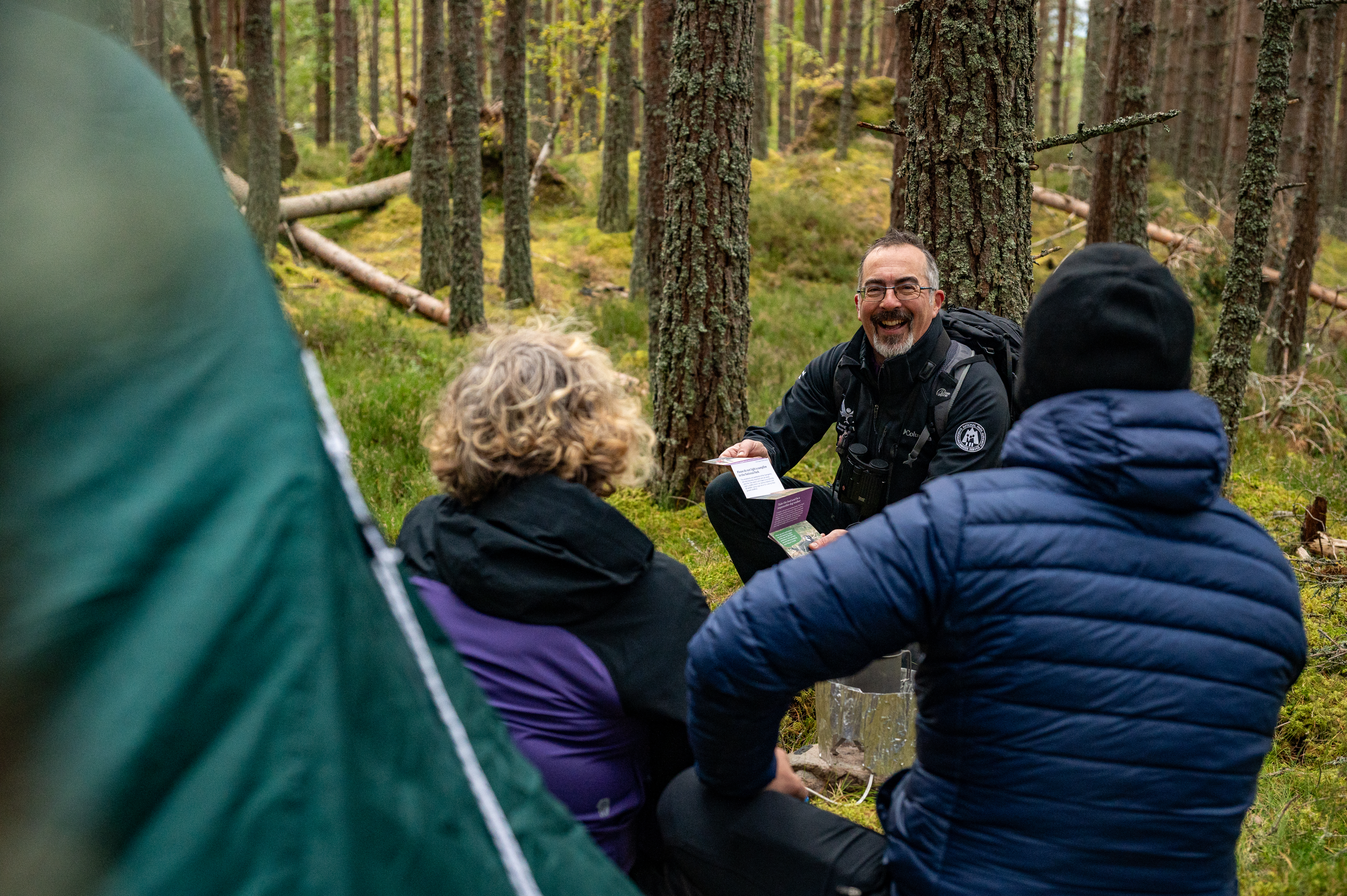 Ranger smiling and talking to campers next to their tent