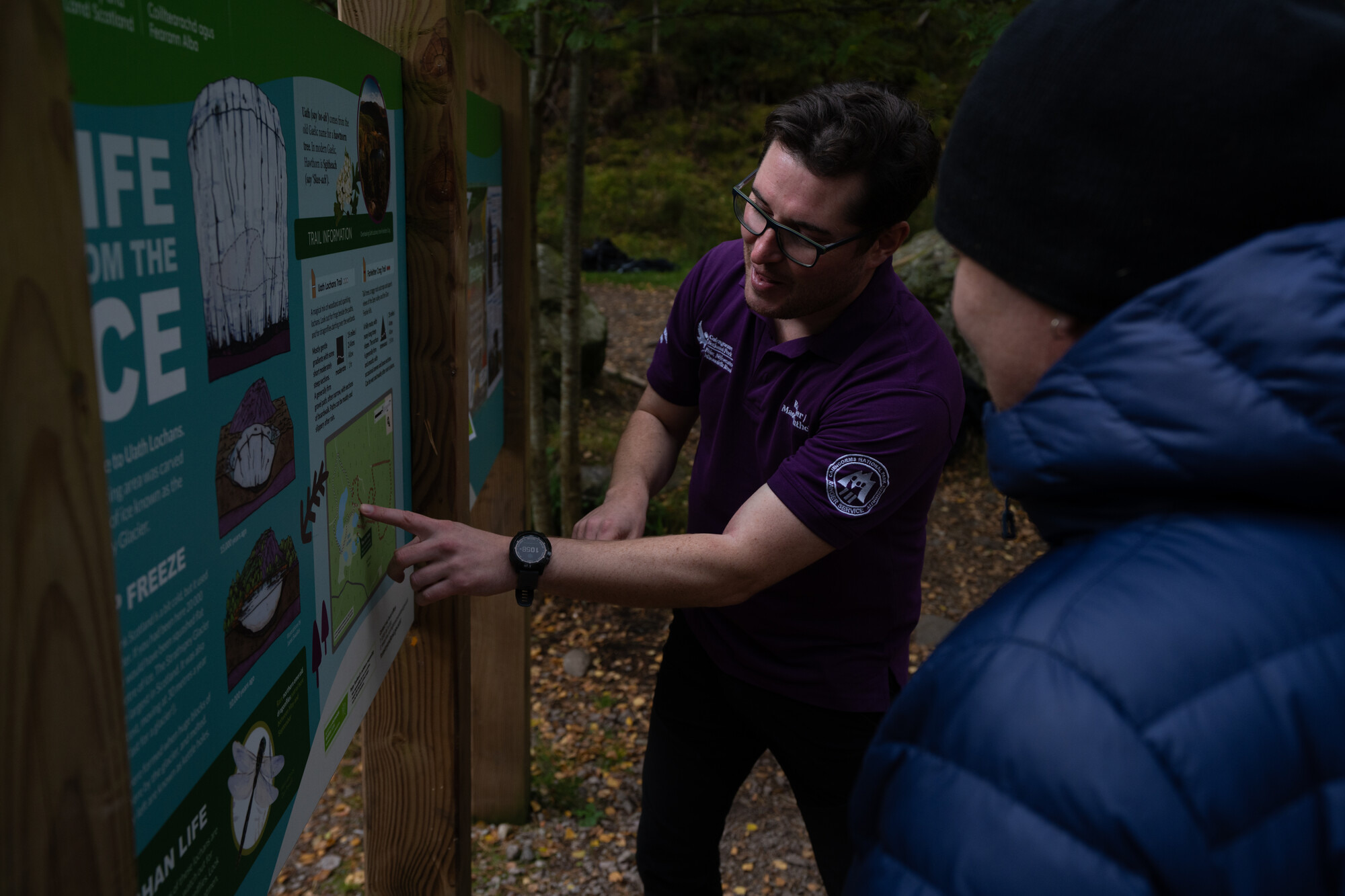 A ranger points at a map on an information sign.