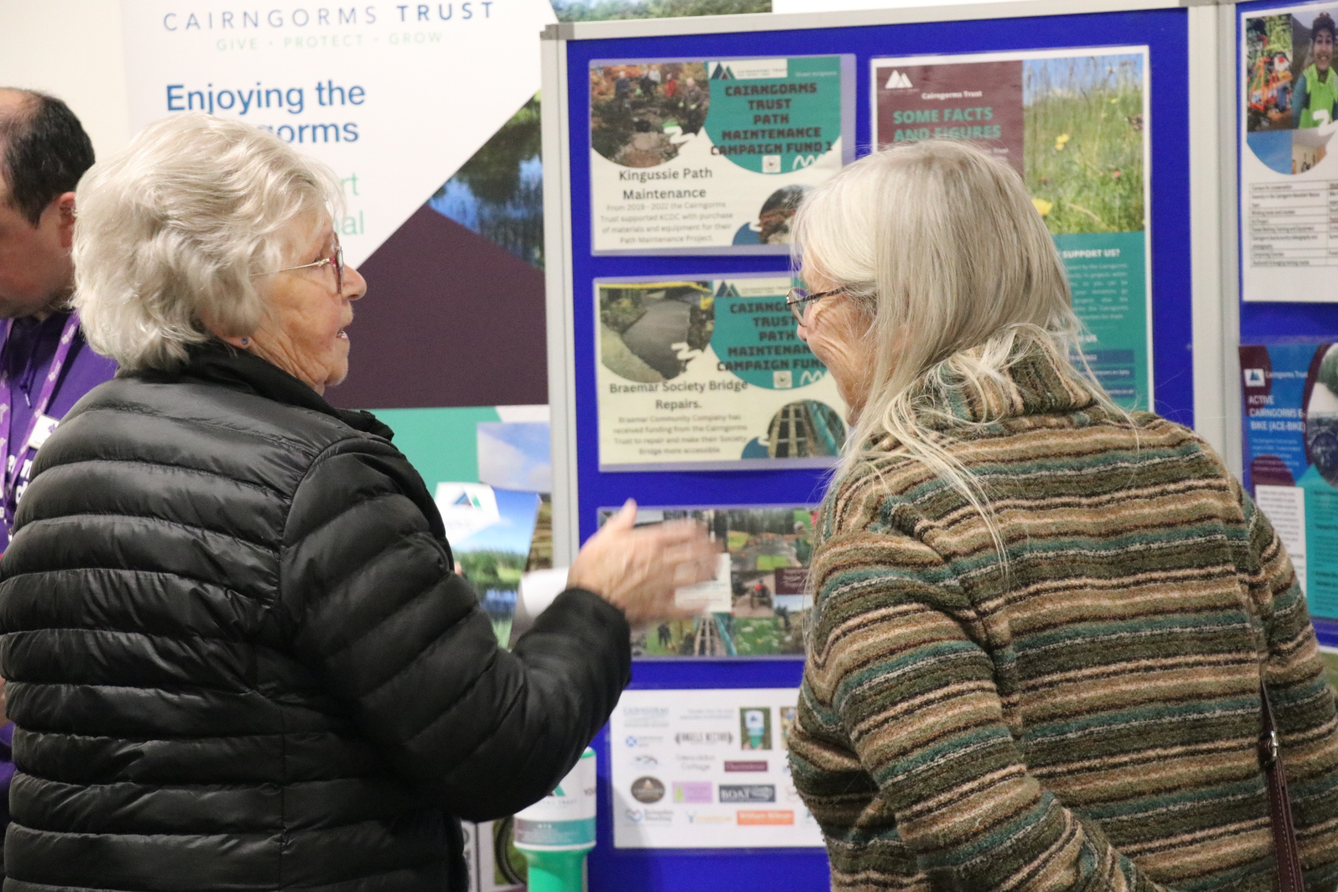 Two people chatting in front of information panels.