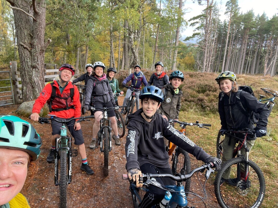 Group of young people on bikes with a forest in the background
