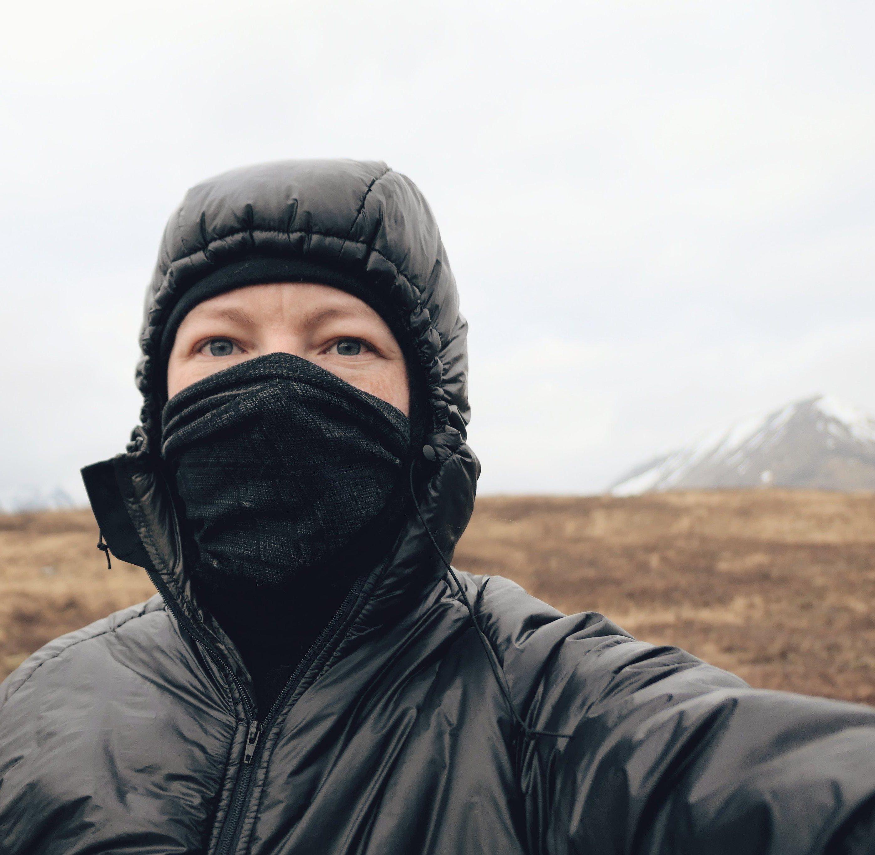 Innes wearing a black jacket and buff over his nose out on the hills.