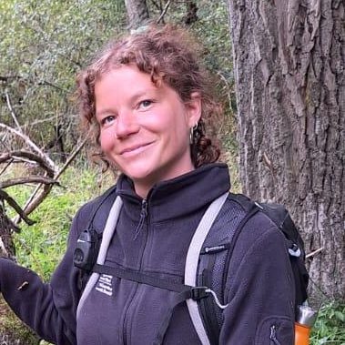 Georgia smiles at the camera in a forest