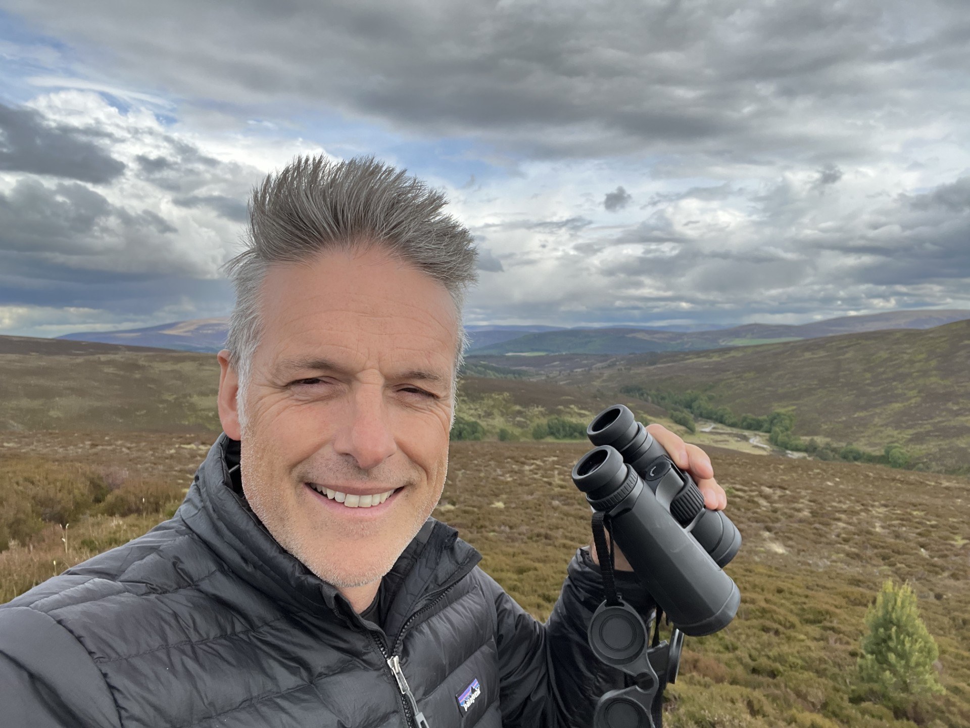 Head and shoulders shot of Nick Baker on a moorland holding binoculars