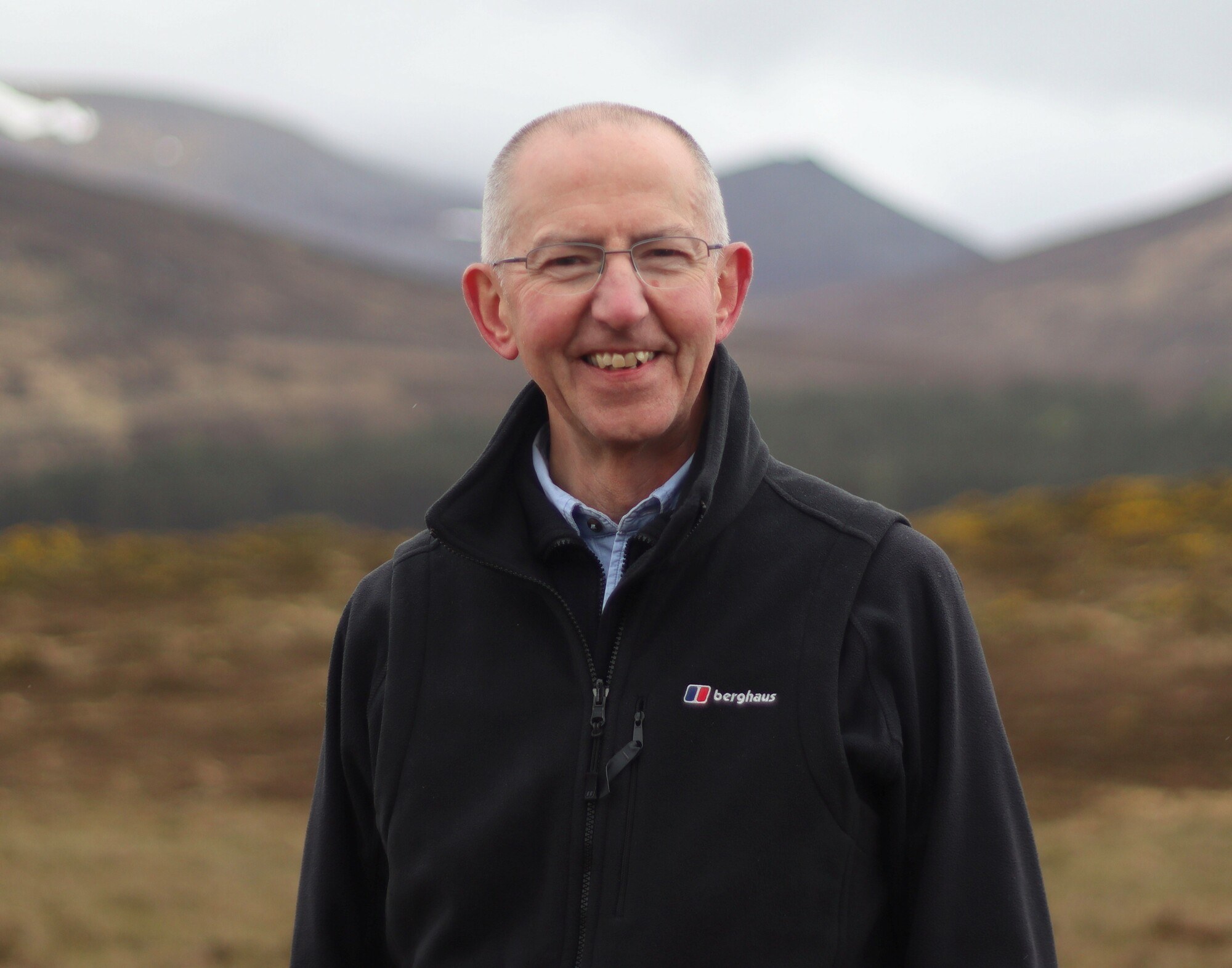 Headshot of board member Sandy Bremner against a backdrop of mountains