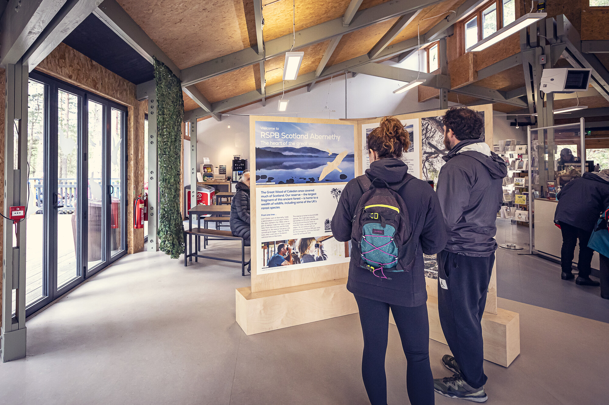 Two people looking at information boards in the RSPB visitor centre at Abernethy
