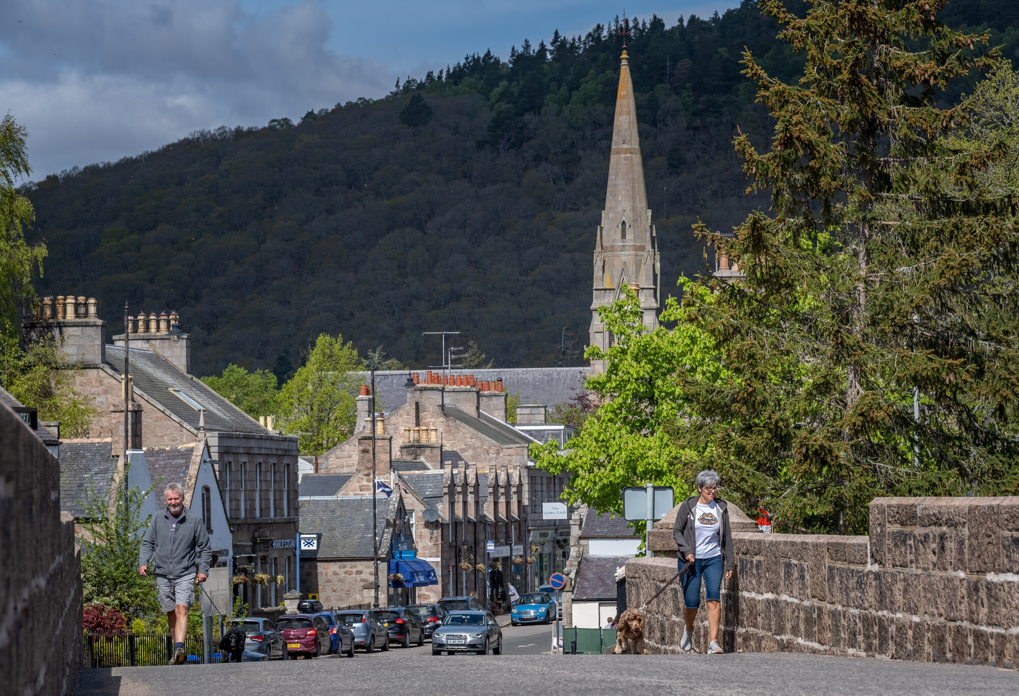 Two people walking dogs on a street in Ballater.
