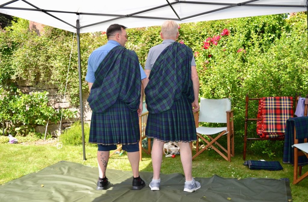 Two men with their backs to camera wearing full Highland Dress