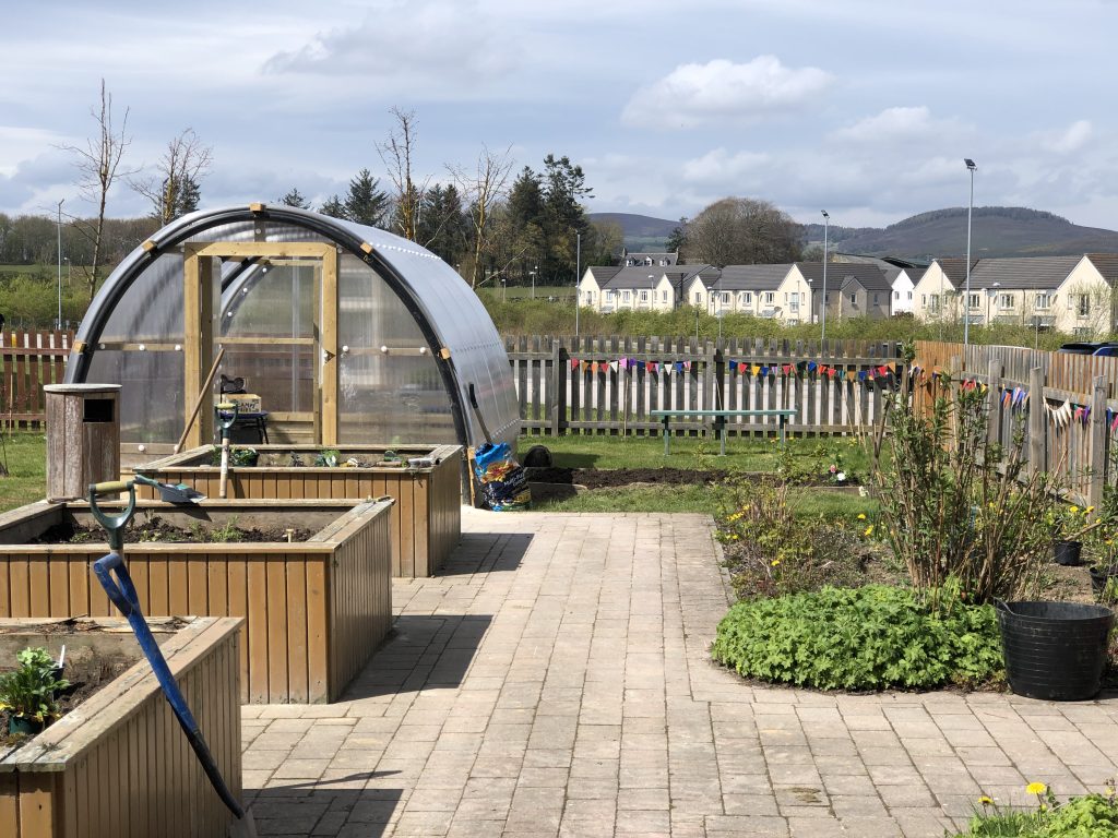 Image of Polycrub with bunting in a garden. 