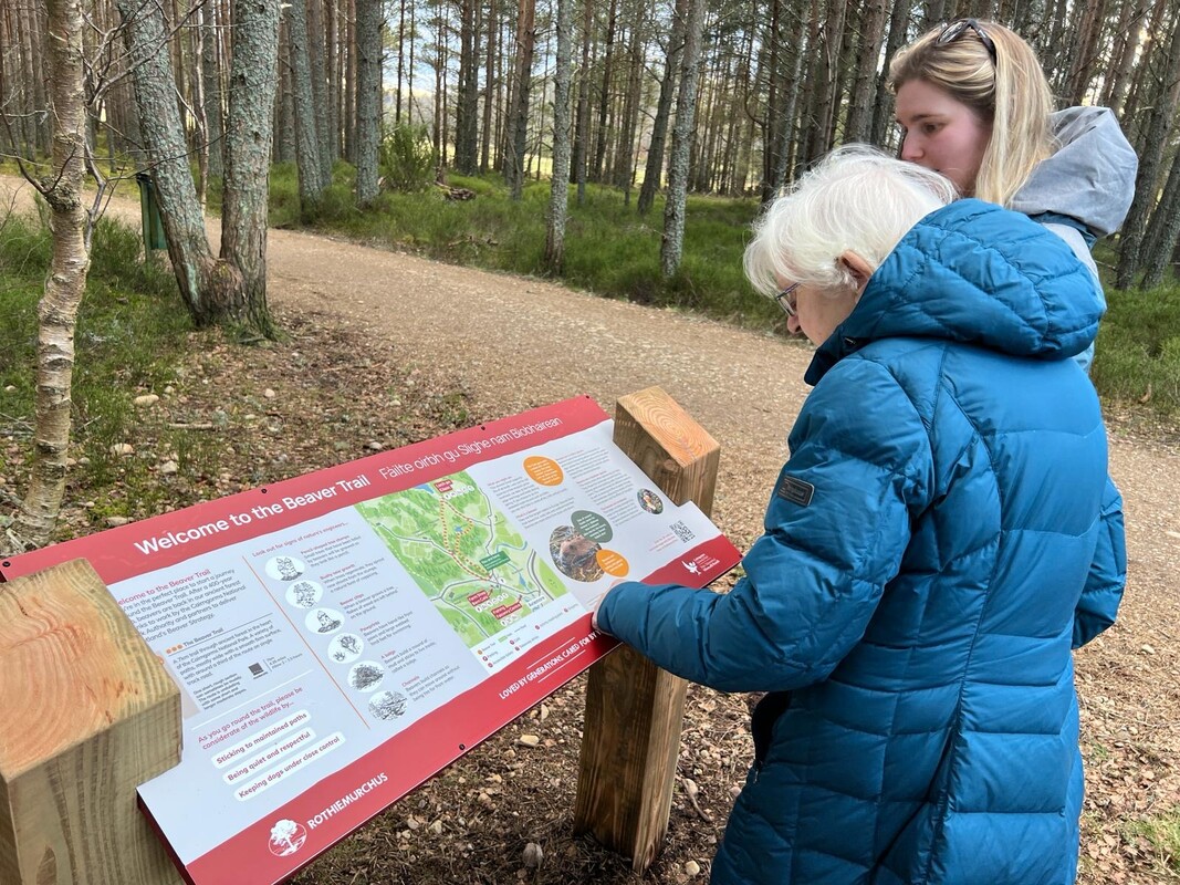 Two women read a beaver trail interpretation panel at Rothiemurchus.